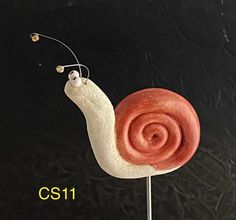 a close up of a cake shaped like a snail on top of a stick with the word cs1 written below it