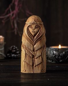 an image of a wooden statue with candles in the background and some pine cones around it