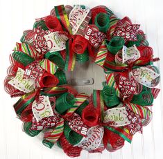 a christmas wreath with red, green and white ribbons hanging from the front of it