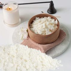 a bowl filled with white rice next to a candle on a plate and some other items