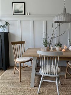 a dining room table and chairs with candles on them in front of a white paneled wall