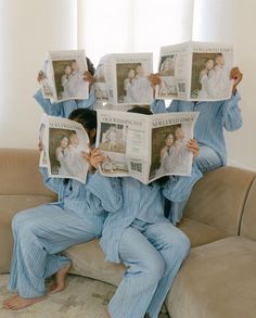 a woman sitting on top of a couch while holding up newspapers in front of her face