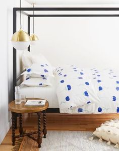 a white bed with blue flowers on it in a bedroom next to a wooden floor