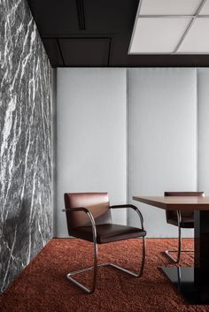 two chairs and a table in an office with marble wall panels on the walls behind them