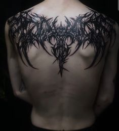 the back of a man's body with black ink on his chest and wings