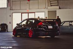 two cars parked in a garage next to each other with red rims on them