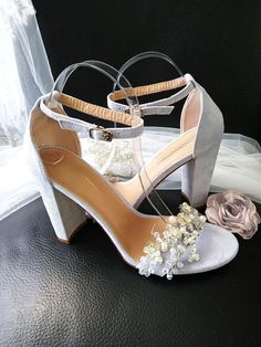 a pair of high heeled shoes with flowers on the side and veil behind them