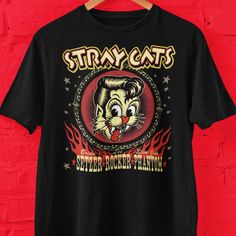 Stray Cats rockabilly band graphic t shirt. Great gift for fans of jazz and rockabilly music. Bella+Canvas 3001 * 100% Airlume combed and ringspun cotton (fiber content may vary for different colors) * Light fabric (4.2 oz/yd² (142 g/m * Retail fit * Tear away label * Runs true to size With side seams Located along the sides, they help hold the garment's shape longer and give it structural support Shoulder tape Twill tape covers the shoulder seams to stabilize the back of the garment and prevent Rockabilly Graphic Print Short Sleeve Top, Retro Band Logo Tops, Retro Pre-shrunk Shirt For Concert, Stray Cats, Rockabilly Bands, Rockabilly Music, Slim Jims, Stray Cat, Tour T Shirts