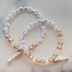 two personalized bracelets with swarong beads and charms on a marble surface