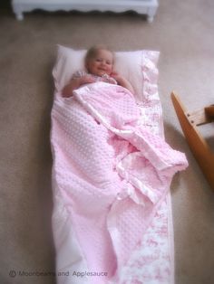 a baby wrapped in a pink blanket laying on the floor