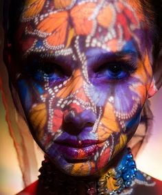 a woman with butterflies painted on her face and body is looking at the camera while posing for a photo