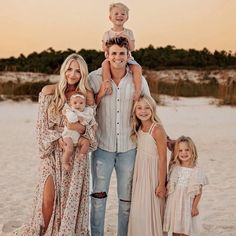 a family poses for a photo on the beach at sunset with their two children and one adult