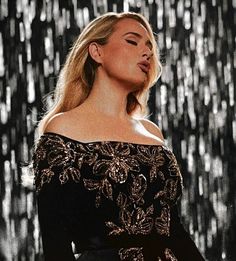 a woman in a black dress with gold sequins on it's shoulders