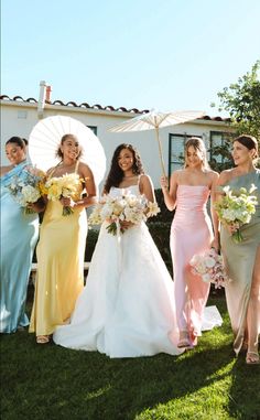 the bridesmaids are all dressed in different colored dresses and holding parasols