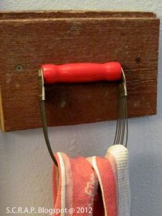 a towel rack with a red handle hanging from it's side on a wall