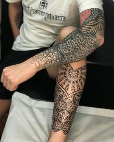 a man sitting on top of a bed with tattoos on his arm and leg,