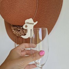 a person holding a wine glass in front of a hat on top of a wall