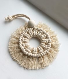 a white tasseled object with a wooden bead hanging from it's center