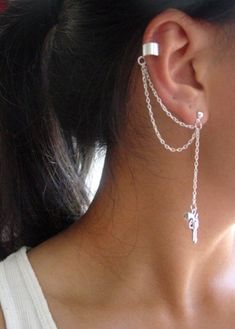 a close up of a person wearing some kind of ear chain with a cross on it