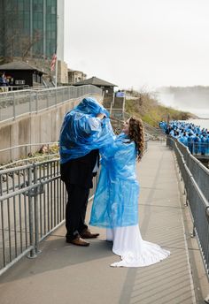 a man and woman standing next to each other on a bridge with blue plastic covering them