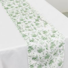 the table is covered with a white and green floral print cloth, which has been folded over it