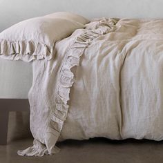 an unmade bed with white linens and ruffled edges