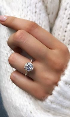 a woman's hand with a diamond ring on her finger and a white sweater