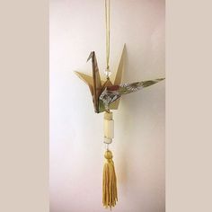 an origami bird hanging from a wall with tassels on it's neck