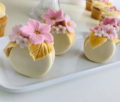 some cupcakes are decorated with pink flowers on top of them and yellow icing