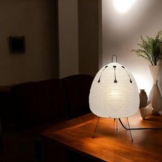 a white lamp sitting on top of a wooden table next to a potted plant