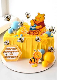 a winnie the pooh birthday cake with honey bears and bees on it's side