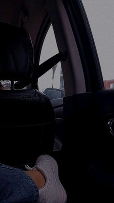 a person sitting in the passenger seat of a car with their feet on the dashboard