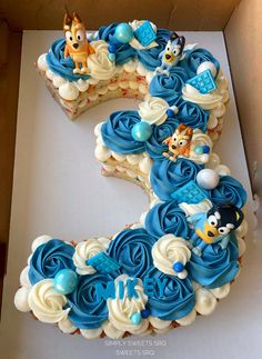 a birthday cake in the shape of the letter s is decorated with blue frosting and cartoon characters