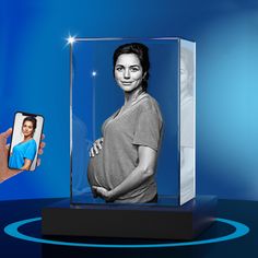 a person holding a cell phone in front of a glass case with a woman's face on it