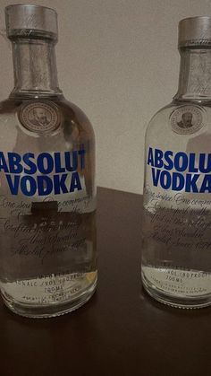 two bottles of absolut vodka are sitting on a table next to each other