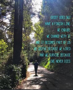 a person walking down a road in the middle of trees and grass with words written on it