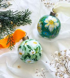 two christmas ornaments sitting on top of a white cloth