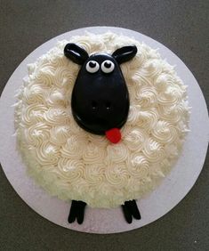 a cake with white frosting and black sheep's head on top, sitting on a plate