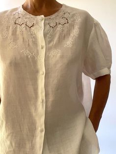 Very beautiful white shirt, made by a seamstress in 100% linen and hand embroidered. (label in Italian: "pure linen, hand embroidered" adorable details: the buttons covered with white fabric; a change button inside pretty puffed sleeves are also embroidered Size: Medium / Large Check with your measurements the model is a Small and measures 1m72 / 5.7' Shirt: - shoulder to shoulder 46 cm / 18" - bust 114 cm / 45" - length 68 cm / 27" Very good condition, fine and quality work **For shipping worldwide, phone number is required, thank you Delivery for France is free via Mondial Relais. Please specify your relay point in a message. Instagram for videos and news: @marinadeprovencevintage Spring Linen Top With Broderie Anglaise, Daywear Embroidered Linen Blouse, Embroidered Linen Blouse For Daywear, Embroidered Linen Button-up Top, Linen Embroidered Button-up Top, Linen Button-up Top With Embroidery, Fitted Linen Blouse With Floral Embroidery, White Linen Top With Broderie Anglaise, White Linen Top With Broderie Anglaise Detail