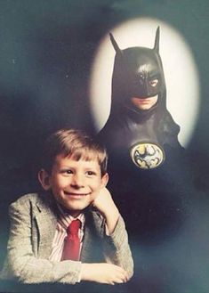 a young boy sitting next to a batman poster with the words sa le on it