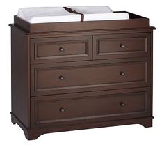 a baby crib with two drawers and white sheets on it's top shelf