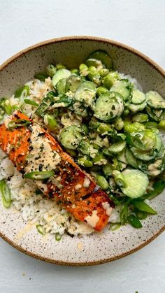 a bowl filled with rice, cucumbers and salmon