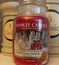 a jar of yankee candle sits on a counter next to other containers with candles in them