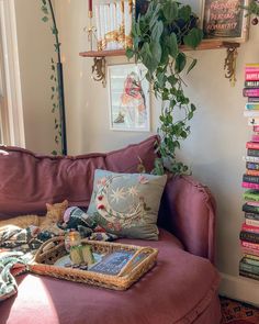 a living room filled with lots of furniture and books on top of a pink couch