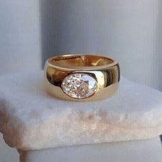 a close up of a gold ring on top of a white stone block with a diamond in the center