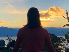 a woman standing in front of a sunset