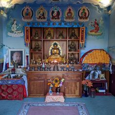 a room filled with lots of buddha statues and other items on display in front of a blue wall