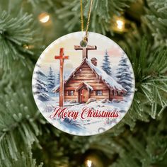 a christmas ornament hanging on a tree with a cross in the center and merry christmas written across it