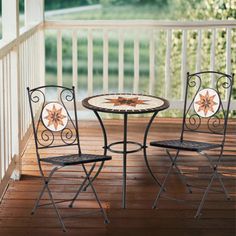 an outdoor table and two chairs on a porch with wood flooring next to it