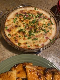 two plates with food on them sitting on a table next to a glass bowl filled with pizza